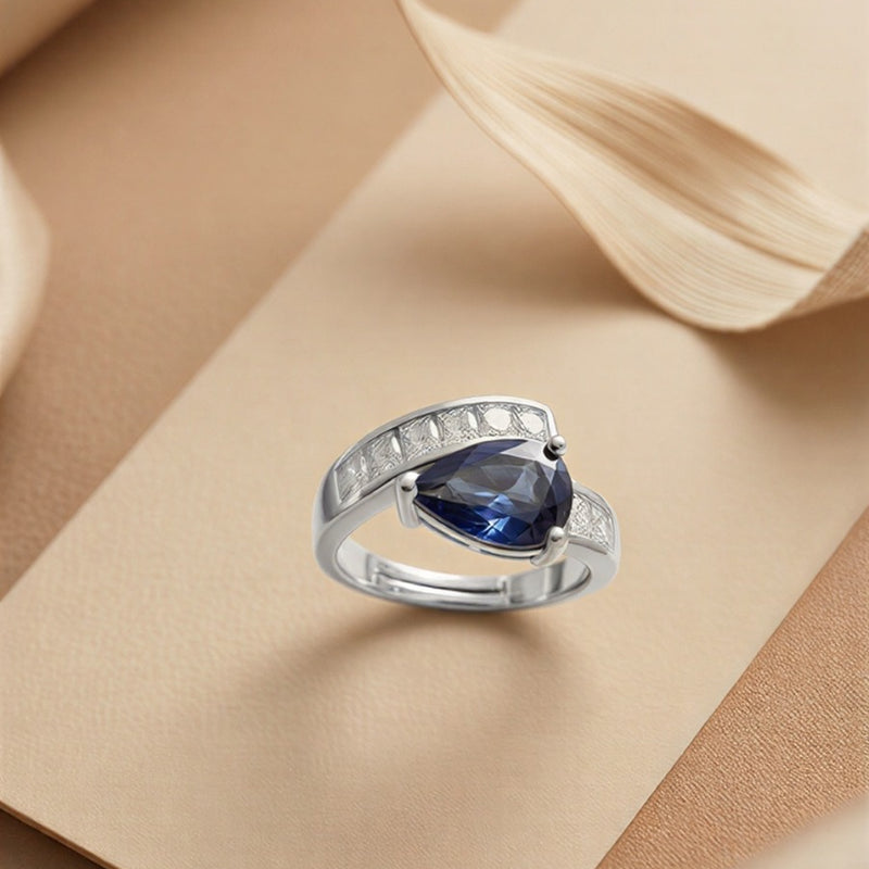 An Avant-Garde Pear-Shaped Deep Blue Solitaire Enveloped in Radiant Crystal Architecture with Dual-Tone Metallic Versatility