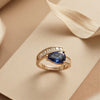 An Avant-Garde Pear-Shaped Deep Blue Solitaire Enveloped in Radiant Crystal Architecture with Dual-Tone Metallic Versatility