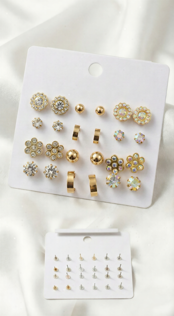A 12-pair gold-tone earring set on a white card featuring iridescent crystal flowers, gold hoops, metallic spheres, and sparkling multifaceted studs.
